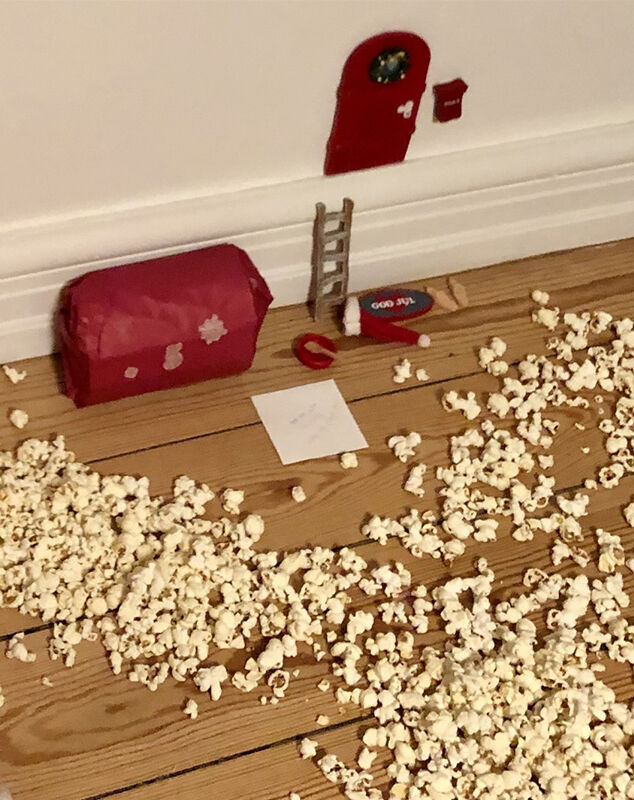 Popcorn ligger på gulvet rundt om et nissehus i røde farver.