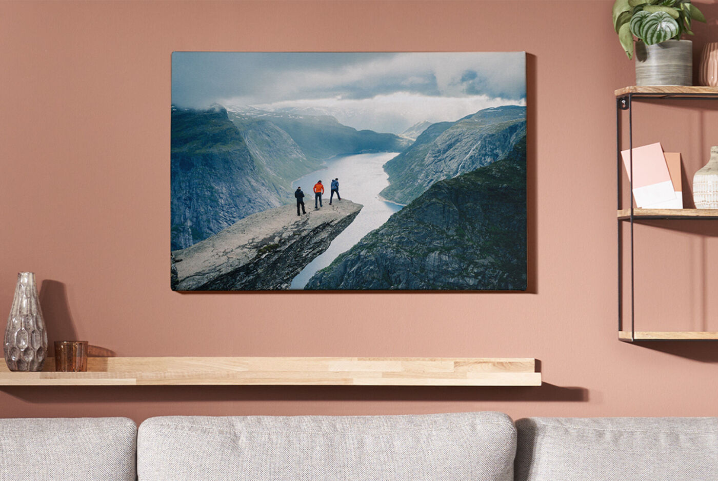 Tre personer står på en klippe og ser på en fjord med bjerge i baggrunden.